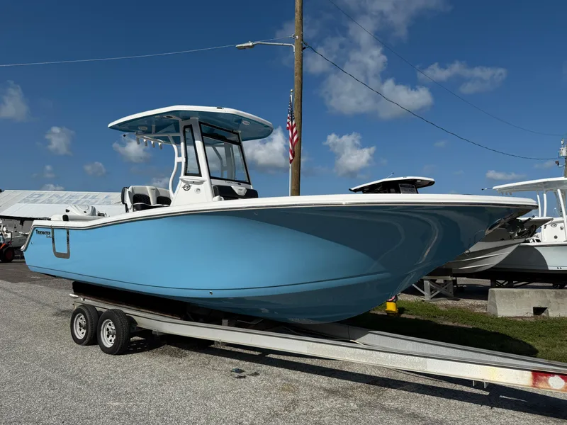 Slide: The Image of 2026 Tidewater 256 LXF boat on trailer, blue hull, clear sky background. - 2