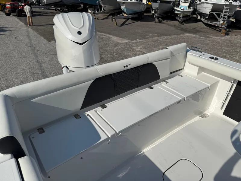 Slide: The Image of 2026 Tidewater 256 LXF boat interior with seating and engine, displayed in a marina setting. - 8