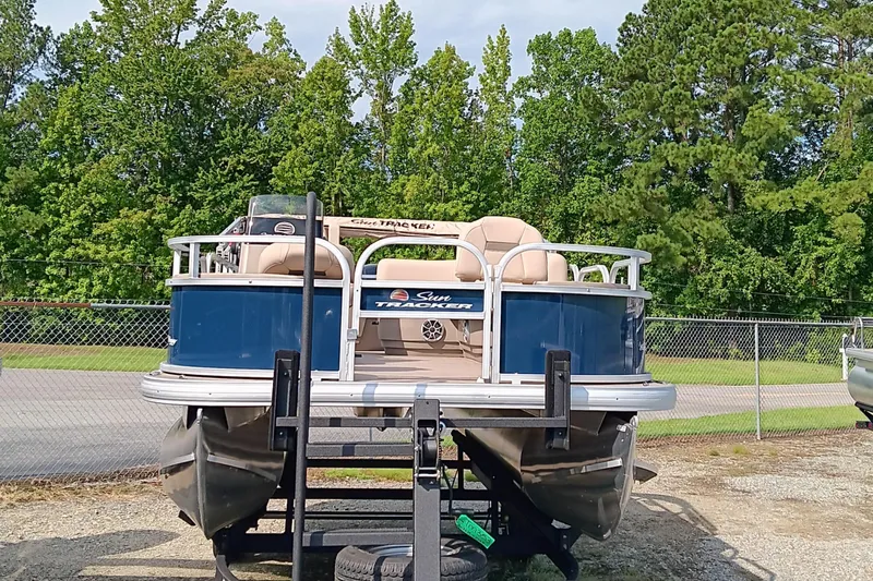 Slide: The Image of 2025 Sun Tracker Bass Buggy 18 DLX pontoon boat on trailer, surrounded by trees. - 3