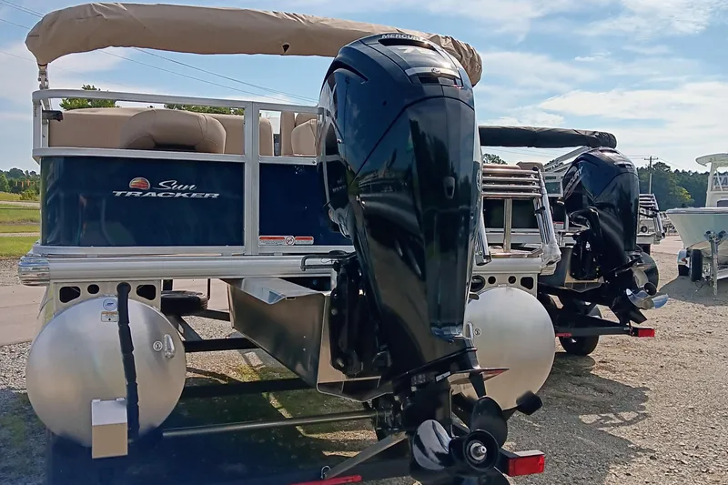Slide: The Image of 2025 Sun Tracker Bass Buggy 18 DLX pontoon boat with Mercury outboard motor, parked outdoors. - 4