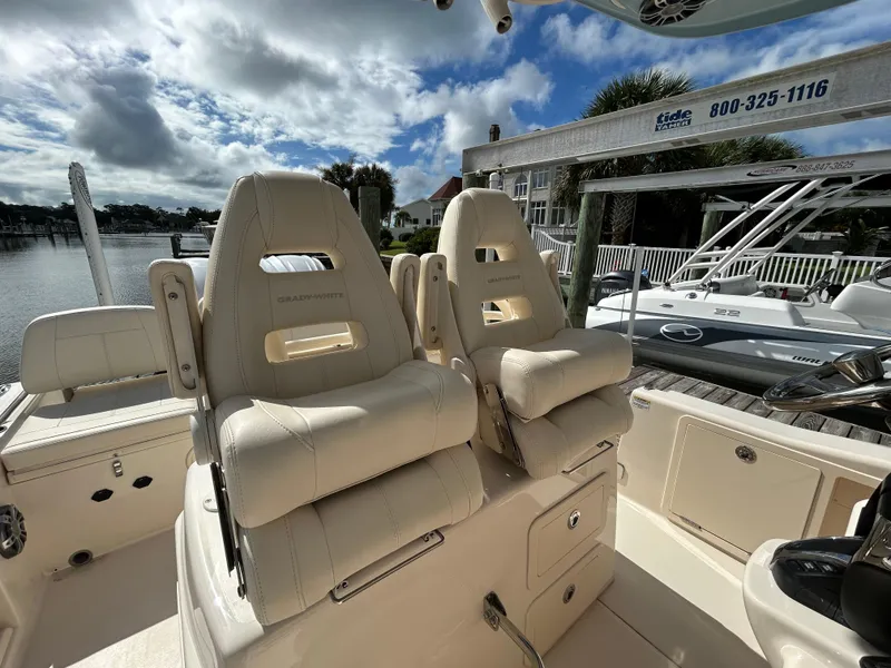 Slide: The Image of 2023 Grady-White 281 Coastal Explorer boat interior with plush seating and marina backdrop. - 8