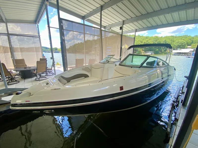 Slide: The Image of 2008 Rinker 246 Captiva Bowrider docked in a covered marina with scenic lake view. - 9