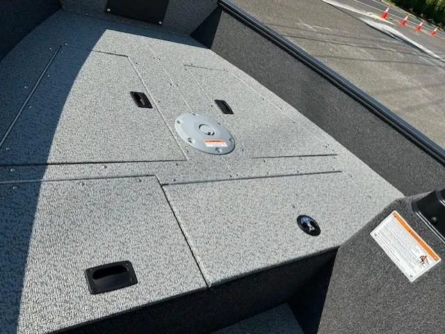 Slide: The Image of 2026 Lund 1650 Angler SS boat interior, featuring a spacious, carpeted deck with storage compartments. - 4