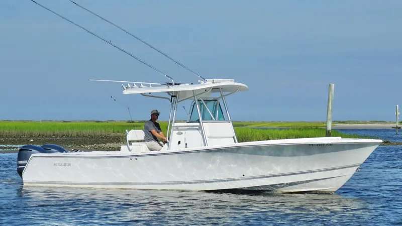 Slide: The Image of 2006 Regulator 32 FS boat on water with person, clear sky, and grassy shoreline. - 3