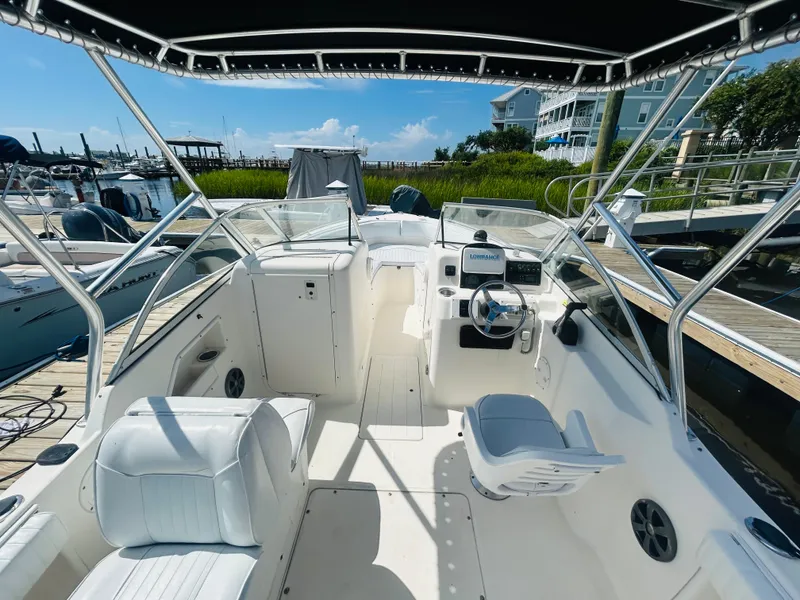 Slide: The Image of 2005 Sea Hunt Escape 220 boat interior with seating and steering wheel at a marina. - 4
