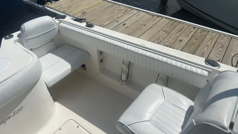 Slide: The Image of 2005 Sea Hunt Escape 220 boat interior with white seating and wooden dock. - 5