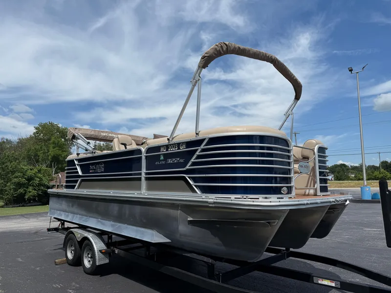 Slide: The Image of 2018 SunCatcher Elite 322 RC pontoon boat on trailer under blue sky. - 3