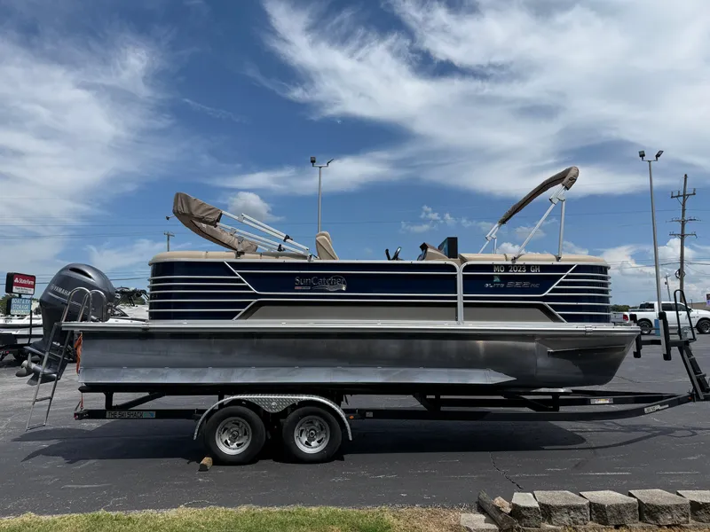 Slide: The Image of 2018 SunCatcher Elite 322 RC pontoon boat on trailer under blue sky. - 4
