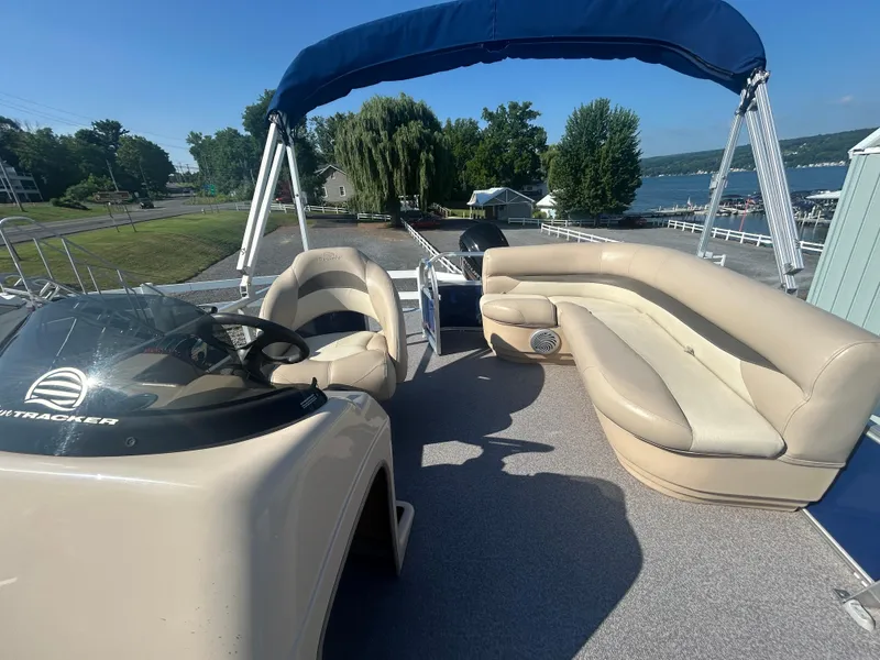 Slide: The Image of 2016 Sun Tracker Party Barge 18 DLX with beige seating and blue canopy, docked by a lake. - 12