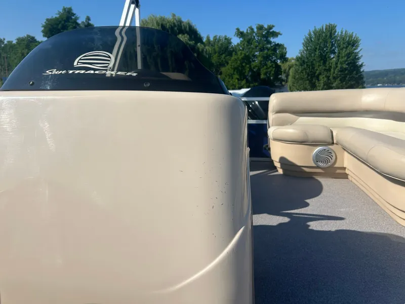 Slide: The Image of 2016 Sun Tracker Party Barge 18 DLX interior with seating and console, under clear blue sky. - 13