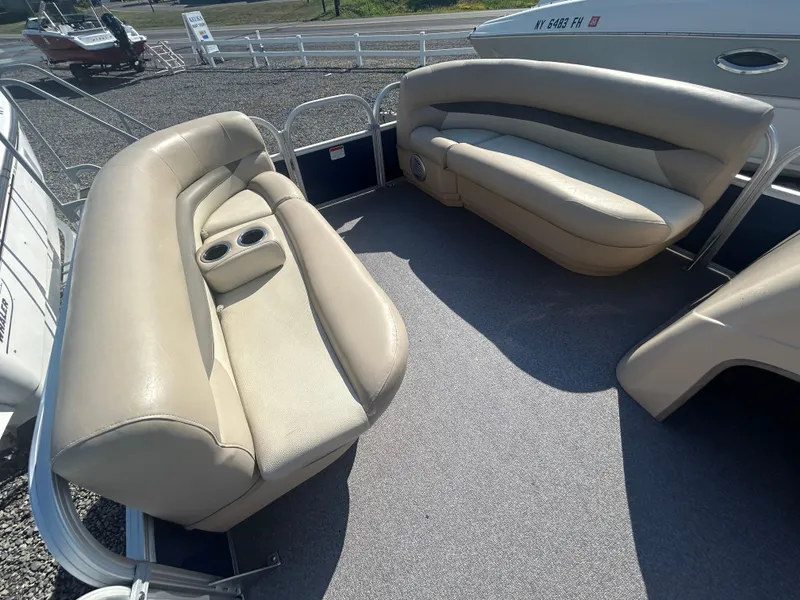 Slide: The Image of 2016 Sun Tracker Party Barge 18 DLX interior with beige seating and cup holders. - 18