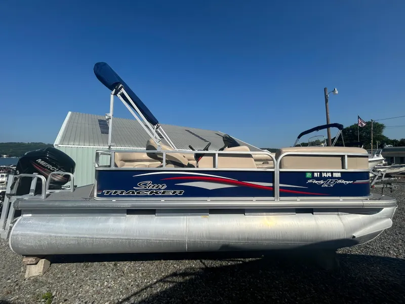 Slide: The Image of 2016 Sun Tracker Party Barge 18 DLX pontoon boat with canopy, parked on gravel. - 4