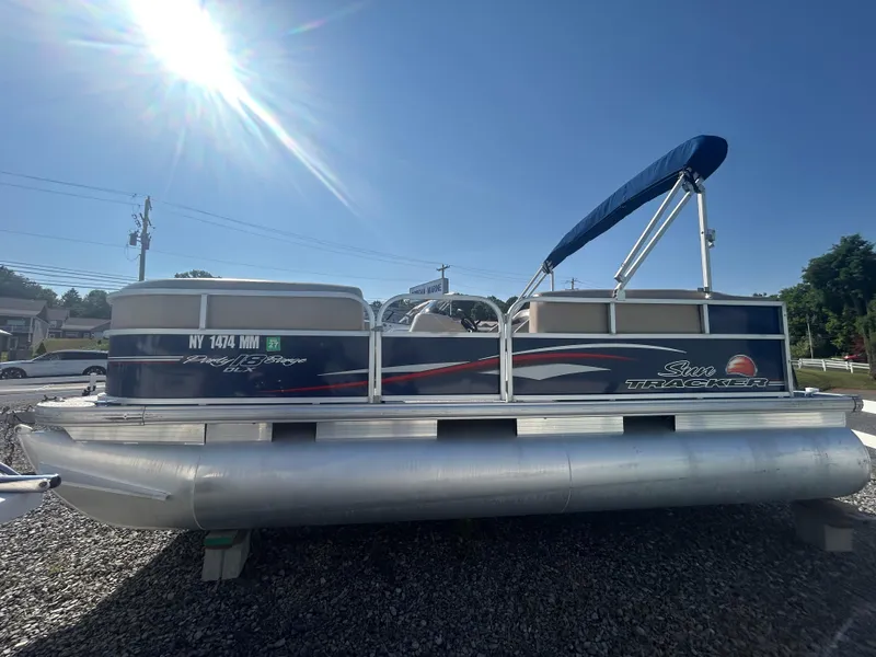 Slide: The Image of 2016 Sun Tracker Party Barge 18 DLX pontoon boat with blue canopy, parked on gravel. - 5