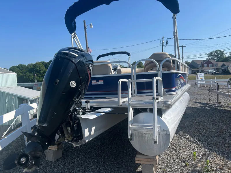 Slide: The Image of 2016 Sun Tracker Party Barge 18 DLX pontoon boat with outboard motor, parked on gravel. - 6
