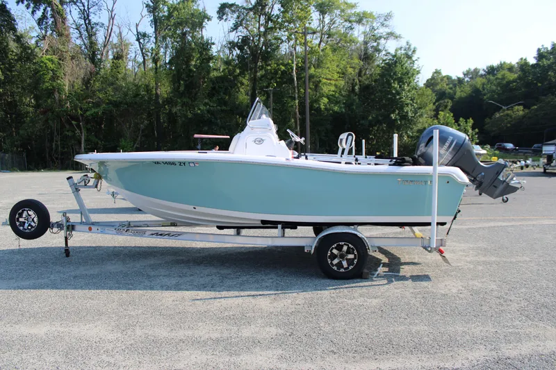 Slide: The Image of 2021 Tidewater 198 CC Adventure boat on trailer, parked in a wooded area. - 0