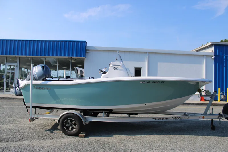 Slide: The Image of 2021 Tidewater 198 CC Adventure boat on trailer, parked outside a blue and white building. - 1