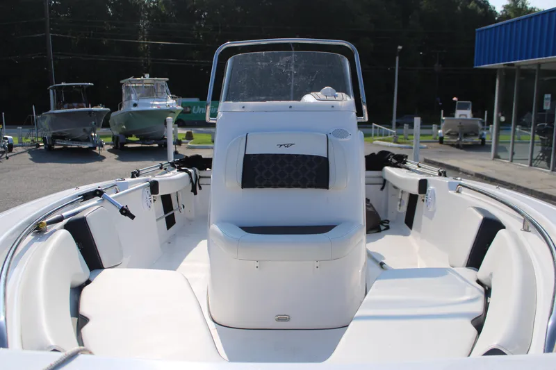 Slide: The Image of 2021 Tidewater 198 CC Adventure boat interior with seating and console, parked outdoors. - 7