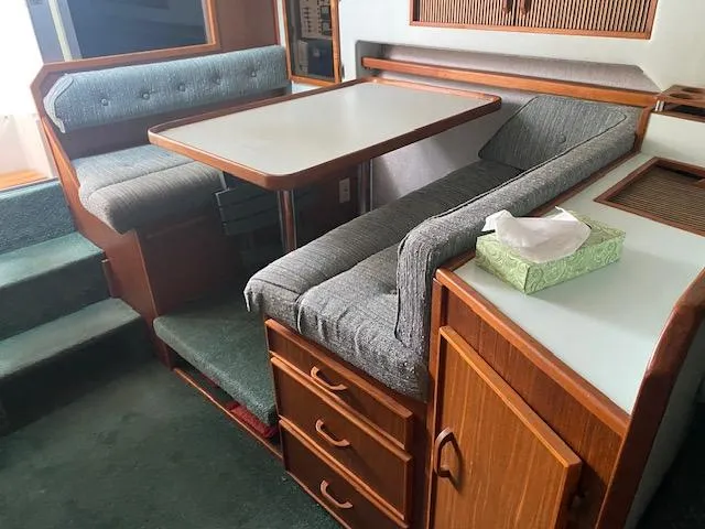 Slide: The Image of 1987 Sea Ray 300 Weekender interior with dining area, cushioned seating, and wooden cabinetry. - 16