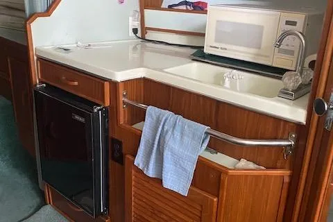 Slide: The Image of 1987 Sea Ray 300 Weekender kitchen with sink, microwave, and mini fridge. - 17
