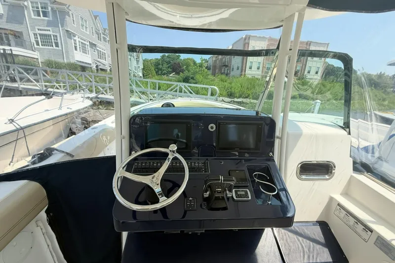 Slide: The Image of 2015 Pursuit ST 310 Sport boat helm with steering wheel and navigation controls. - 12
