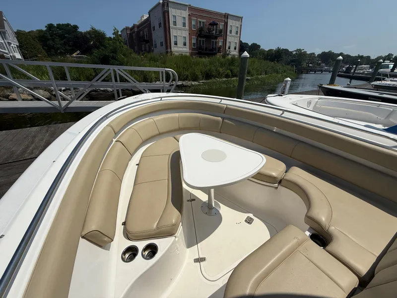 Slide: The Image of 2015 Pursuit ST 310 Sport boat with beige seating and table, docked near waterfront homes. - 13