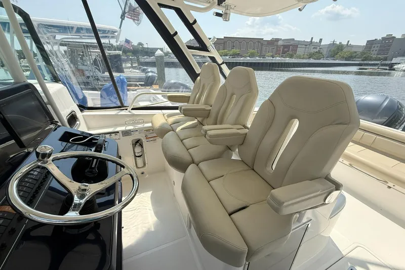 Slide: The Image of Interior of 2015 Pursuit ST 310 Sport boat with beige seats and steering wheel. - 16