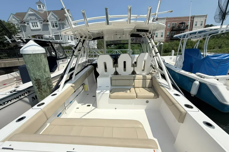 Slide: The Image of 2015 Pursuit ST 310 Sport boat with spacious seating, docked near waterfront homes. - 6