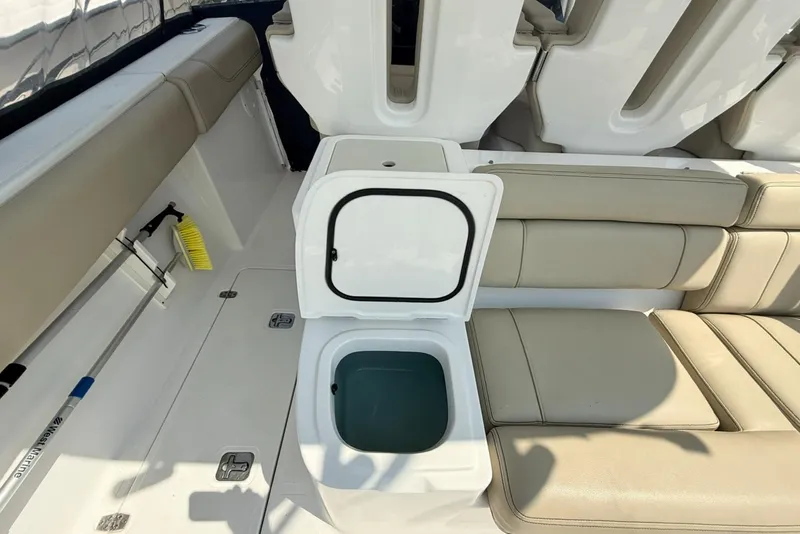Slide: The Image of 2015 Pursuit ST 310 Sport boat interior with open storage compartment and beige seating. - 9