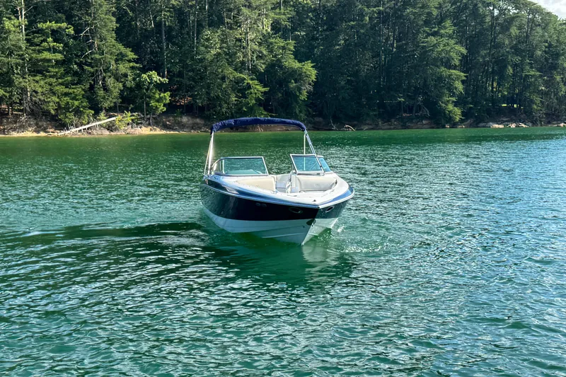 Slide: The Image of 2006 Cobalt 240 boat cruising on a serene lake with lush forest backdrop. - 13