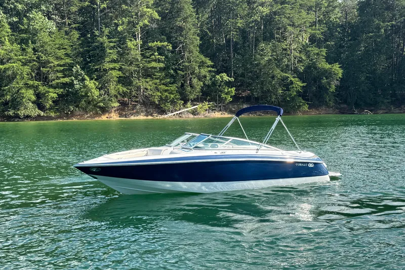 Slide: The Image of 2006 Cobalt 240 boat on a serene lake with lush forest backdrop. - 16
