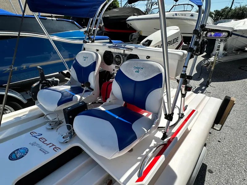 Slide: The Image of 2020 CraigCat E2 Elite with blue and white seats, parked among other boats. - 7
