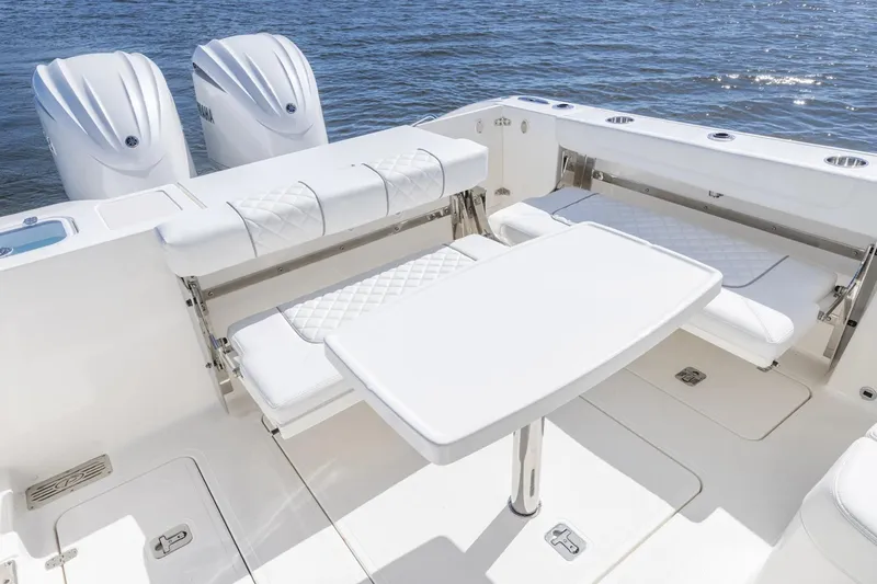 Slide: The Image of 2026 Pursuit DC 306 Dual Console boat interior with seating and table on water. - 12