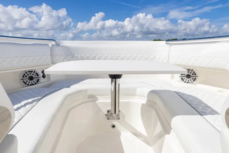 Slide: The Image of 2026 Pursuit DC 306 Dual Console boat interior with white seating and table under blue sky. - 9