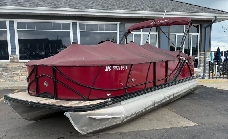 Slide: The Image of 2018 South Bay 523CR pontoon boat with red cover, parked near a building. - 6
