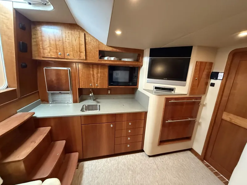 Slide: The Image of 2007 Albemarle 410 Express Fisherman interior with wood cabinetry, kitchenette, and built-in TV. - 22