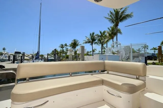 Slide: The Image of 2015 Carver C34 Command Bridge with beige seating, docked near palm trees and clear blue sky. - 12