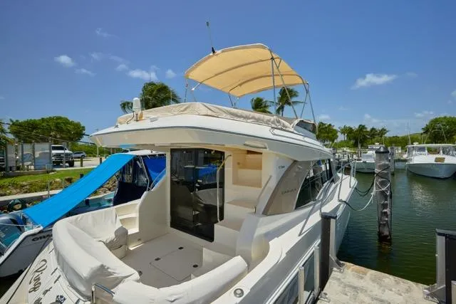 Slide: The Image of 2015 Carver C34 Command Bridge yacht docked, featuring spacious deck and canopy under clear skies. - 21