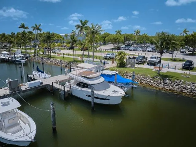 Slide: The Image of 2015 Carver C34 Command Bridge yacht docked at a marina with palm trees and parked cars. - 36