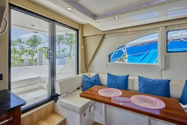 Slide: The Image of Interior of 2015 Carver C34 Command Bridge yacht with seating and table, featuring blue cushions. - 5