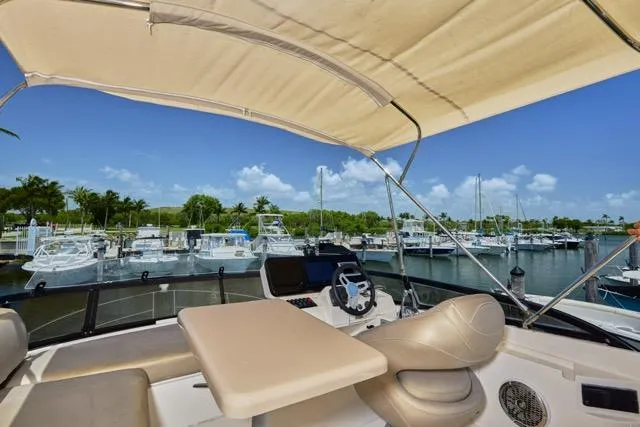 Slide: The Image of 2015 Carver C34 Command Bridge yacht interior with marina view, featuring helm and seating area. - 16