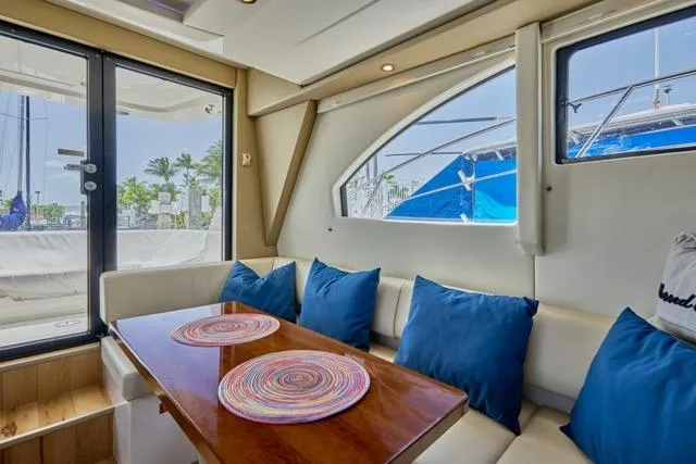 Slide: The Image of Interior of 2015 Carver C34 Command Bridge with blue cushions and wooden table. - 2