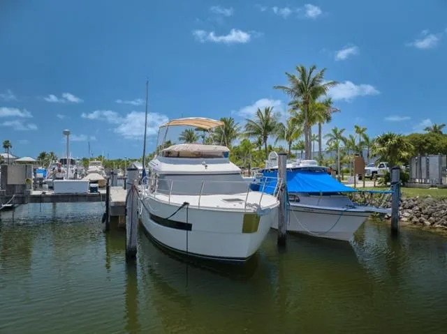 Slide: The Image of 2015 Carver C34 Command Bridge yacht docked in a sunny marina with palm trees. - 26