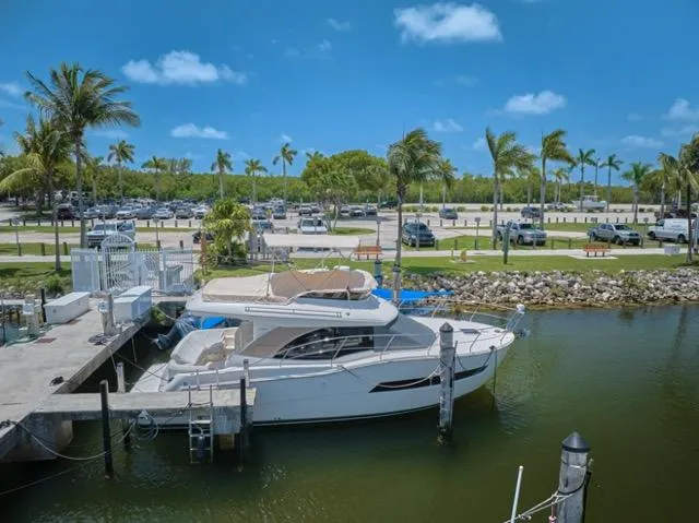 Slide: The Image of 2015 Carver C34 Command Bridge yacht docked in a sunny marina with palm trees. - 34