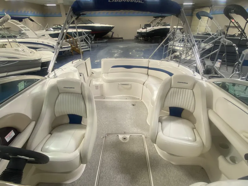 Slide: The Image of 2002 Chaparral Sunesta 243 boat interior with white seating and blue accents in showroom. - 6