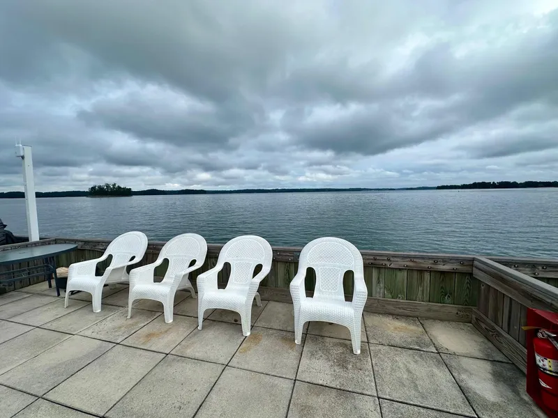 Slide: The Image of Four white chairs on a lakeside deck under cloudy skies, Sumerset 14x66, 1992. - 15