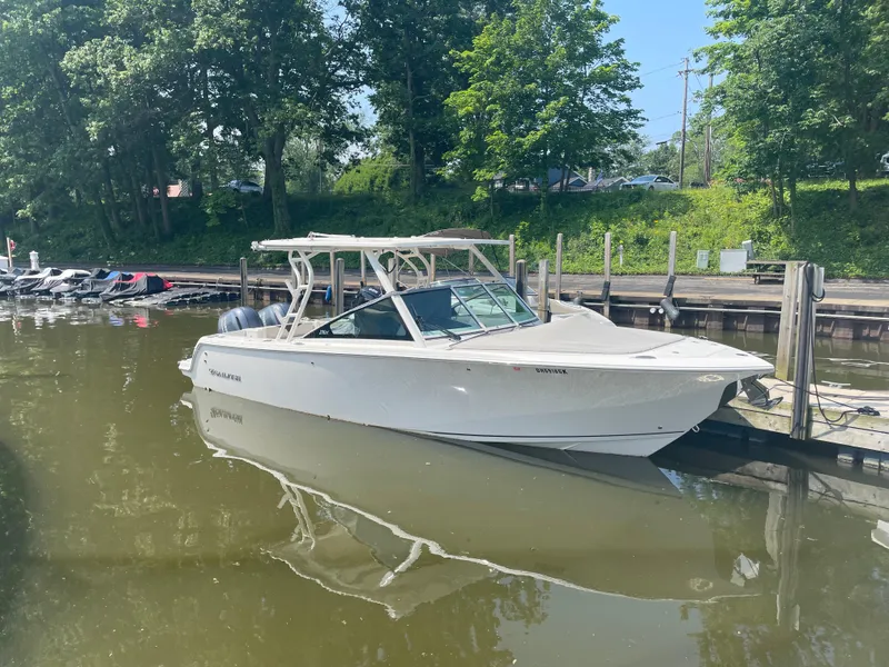 Slide: The Image of 2023 Sailfish 276 DC boat docked, surrounded by trees. - 1