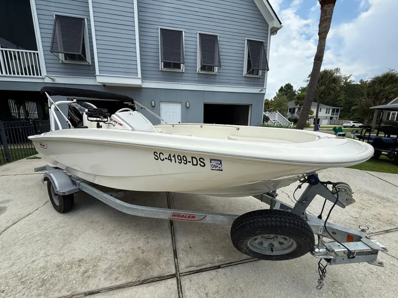 Slide: The Image of 2022 Boston Whaler 160 Super Sport boat on trailer, parked in residential driveway. - 3