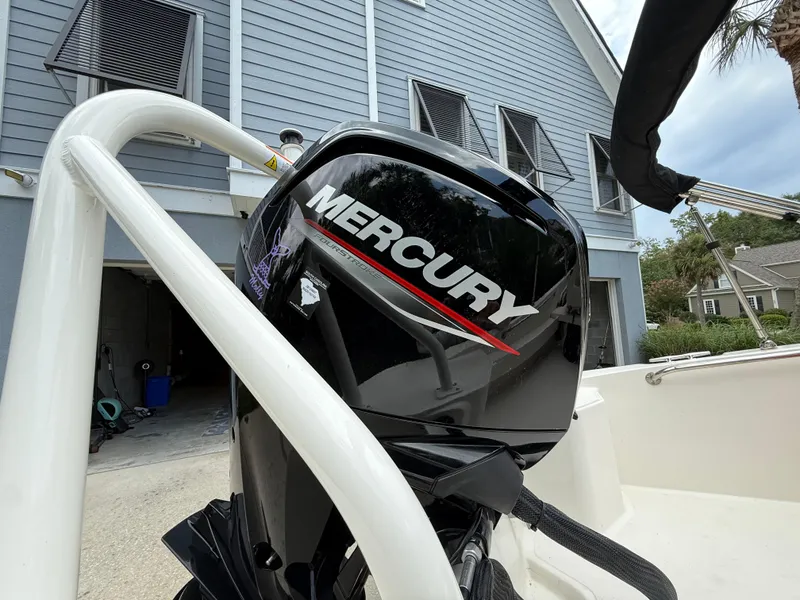 Slide: The Image of Mercury engine on a 2022 Boston Whaler 160 Super Sport boat, parked near a house. - 6