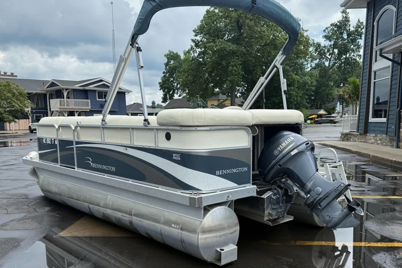 Slide: The Image of 2009 Bennington 1850GL pontoon boat with Yamaha motor, parked outdoors on wet pavement. - 1