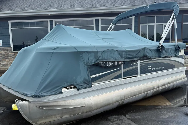 Slide: The Image of 2009 Bennington 1850GL pontoon boat with blue cover, parked near a building. - 11